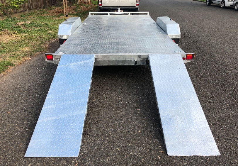 Car trailer with twin loading ramps deployed for vehicle loading